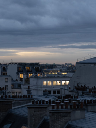 Des fenêtres allumées sous un ciel un chouïa dramatique.