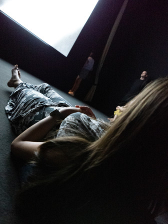 Mon amie étendue au sol face à la projection. La pièce est obscure et la lumière de l'écran l'éclaire.