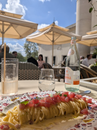 Des pâtes super chères et bonnes à la fois, on aperçoit le sommet de la Tour Eiffel derrière le parasol.