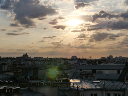 Le soleil qui perce entre les nuages, au dessus des toits parisiens.