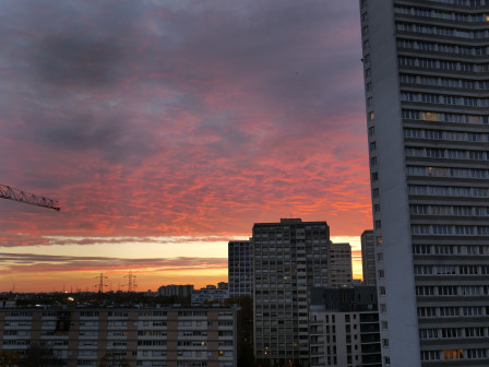 Les nuages moutonnant roses du lever de soleil sur les tours moches qui m'entourent.