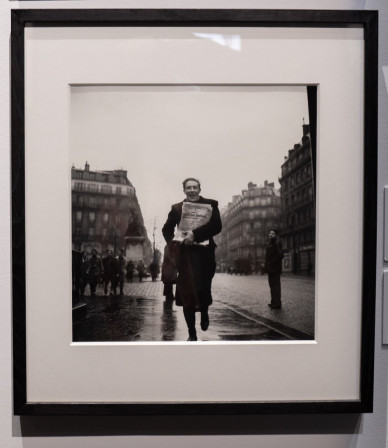 Un crieur de journaux au large sourire, dans la rue, à la libération de Paris.