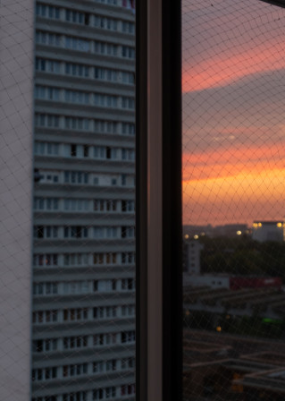 L'immeuble d'en face et le lever du soleil reflété dans les filtres anti-chaleur des fenêtres de ma cuisine.