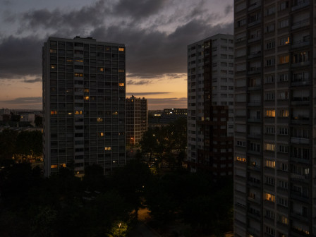 Le ciel ocre pâle et les immeubles d'en face de chez moi à la tombée du jour, avec de gros nuages gris foncé qui s'effilochent par le haut.