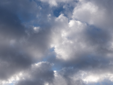 Du ciel bleu entre des nuages dont les couleurs vont du blanc au gris.