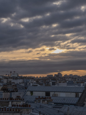 Les toits de Paris, gris, beaucoup de nuages asses massifs et gris, et entre les interstices, la lumière ocrée du soleil qui vient de se lever et filtre comme il peut.