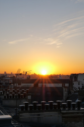 Le soleil quasi sorti de derrière l'horizon. Au dessus, quelques nuages dessinent une forme d'oiseau géant.