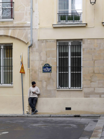 Un jeune homme adossé à un mur.